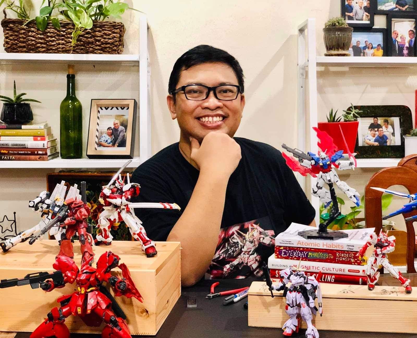 Kuya Aries at home with his built GunPla models on the desk in front of him